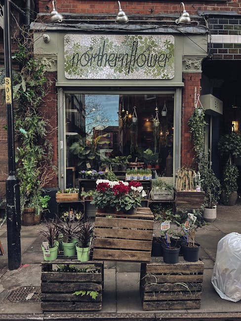 The image depicts the storefront of Northern Flower, a flower shop situated in a brick building with a decorative sign above the window. In front of the shop, there are wooden crates stacked to create